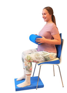 kvinne sitter på stol og holder en pølle og utfører øvelser for bekkensmerter ved hjelp av svangerskapspakken