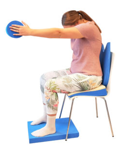 kvinne sitter på stol med utstrakte armer som holder en pølle og utfører øvelser for bekkensmerter ved hjelp av svangerskapspakken